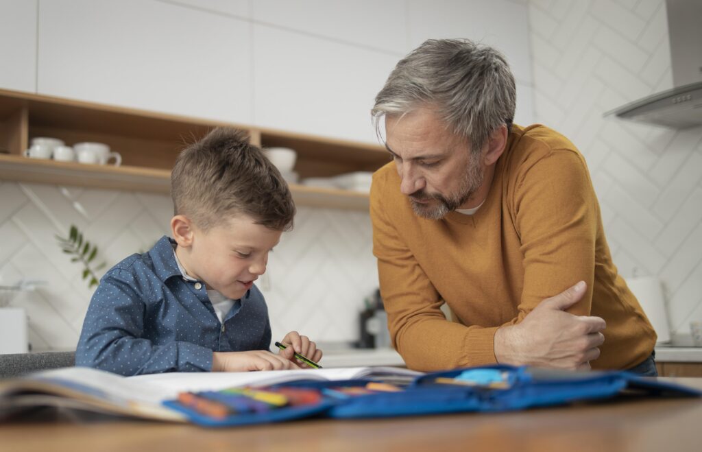 Vader helpt zijn zoon aan de keukentafel met het maken van huiswerk