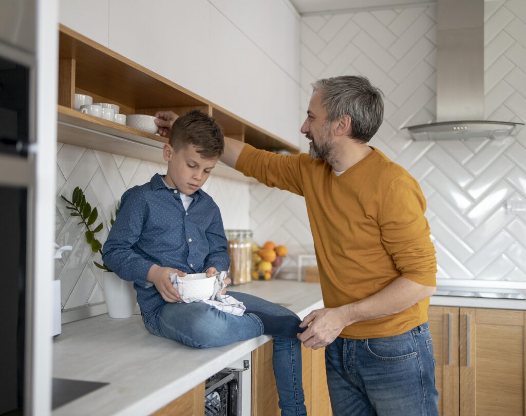 Jongen helpt vader bij de afwas